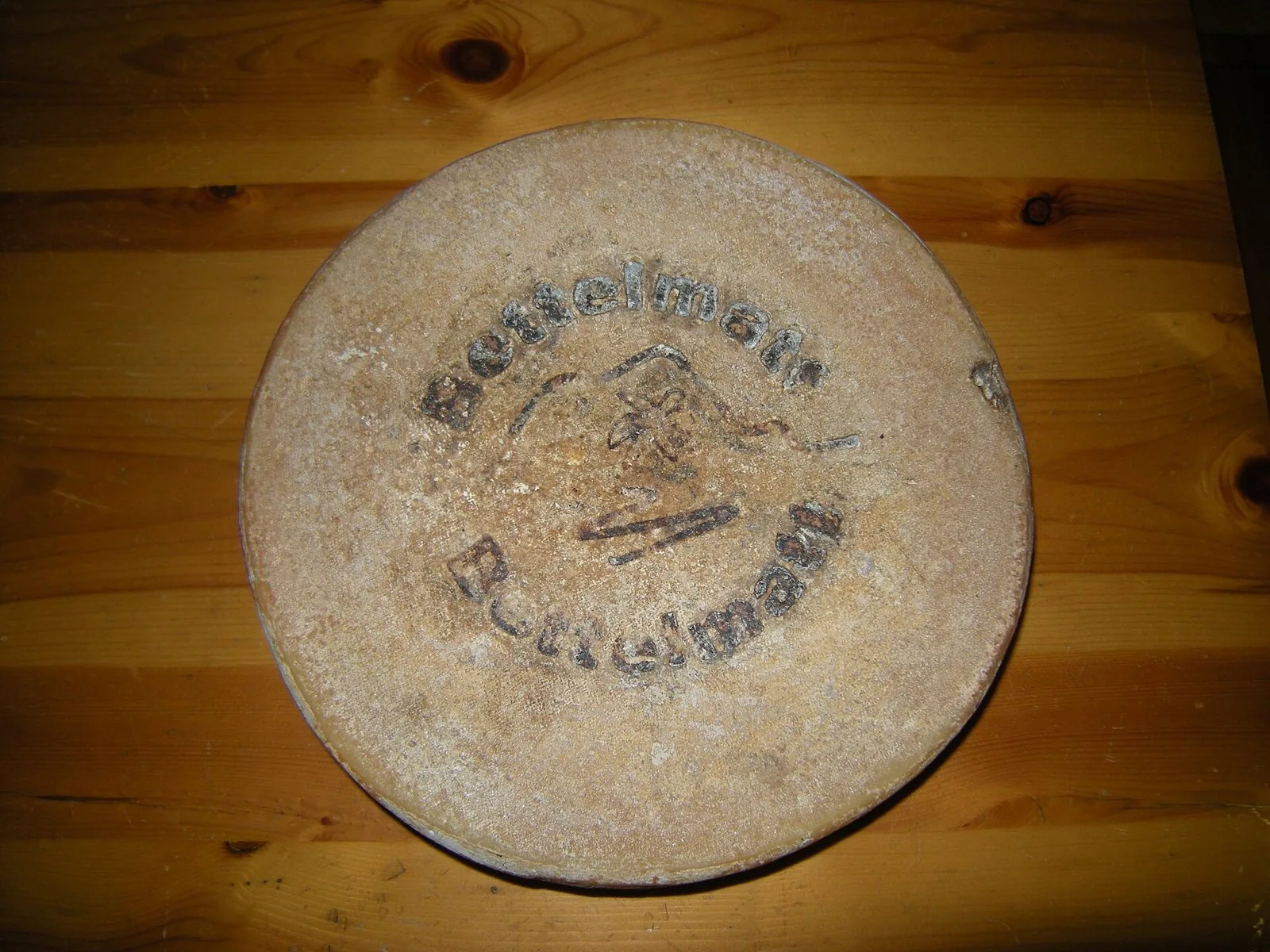 Forma di Bettelmatt con il nome impresso sulla crosta, appoggiata su un tavolo di legno